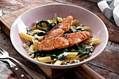 Pieces of baked salmon with spinach, blue cheese, and penne