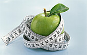 A green apple with a measuring tape