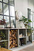Zimmerpflanzen und Spiegel auf offenem Regal mit Kaminholz