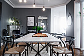 Classic chairs around dining table with marble top in room with grey walls