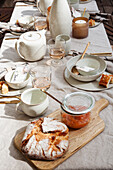 Outdoor table set with ceramic dishes, homemade apricot jam and fresh bread