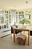 Dining table with leather chairs and bench in light-flooded conservatory