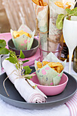 Linen napkin decorated with twig and small bowls of homemade crisps on a festive table