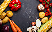 Assorted raw fresh uncooked vegetables on black dark stone background