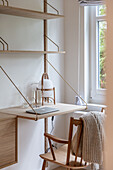 Minimalist, wall-mounted shelving combination with desk made from pale wood