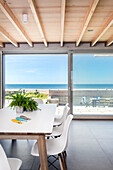 Esstisch vorm Panoramafenster mit Blick aufs Meer und den Balkon