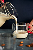 Pouring homemade almond milk into a glass