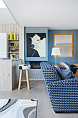 Blau-weiß bezogenes Sofa vor Kuh-Portrait und Küchentheke in offenem Wohnraum