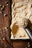 Schokoladen-Kokos-Eiscreme im Metallbehälter und Eisportionierer mit einer Kugel Eis