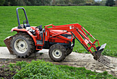 Red tractor on a path amidst fields
