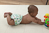 Baby boy in nappy lying on floor with toys