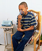 Boy sitting in chair inhaling from nebuliser