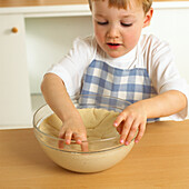 Boy with hand in bowl of dough