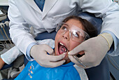 Dentist holding mirror in girl's mouth