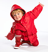 Toddler wearing red raincoat and wellington boots