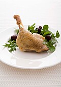 Duck Confit on a white plate with salad garnish