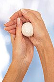 Woman rolling golf ball over thumb joints