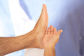 Man tapping sole of foot with side of palm