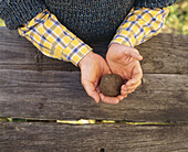 Man holding ball of clay soil in palms of hands