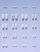 Selection of white pills and capsules arranged in pairs