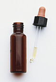 Brown glass bottle of medicine with dropper lying at side