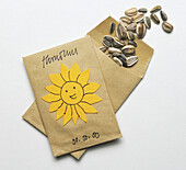 Two brown paper envelopes with sunflowers seeds spilling out