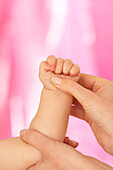 Reflexologist massaging baby's hand using gentle thumb-press