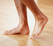 Bare feet of male walking on laminated floor