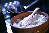 Sushi rice in wooden rice tub with rice paddle