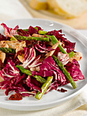 Warm chicken salad with asparagus and red cabbage on plate