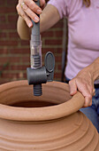 Holding a delivery pipe and water flow adjuster above a pot