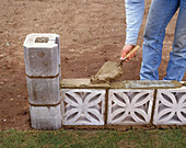 Man holding trowel to spread cement on concrete block