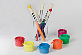 Pots of paint with lids on and selection of paintbrushes