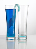 Blue liquid flowing from one glass into another glass