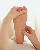 Reflexologist stretching sole of foot with holding hand