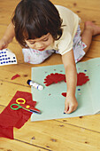 Girl toddler sticking a star on a piece of coloured paper