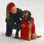 Girl drying wet brown mongrel with red towel