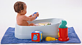 Baby having bubble bath in child's bathtub