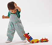Baby pulling wooden toy train set along on piece of string