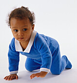 Baby wearing blue jumpsuit, crawling