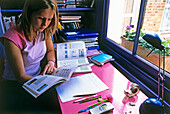 Teenage girl at desk reading textbooks
