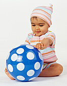 Baby girl sitting behind an inflatable ball