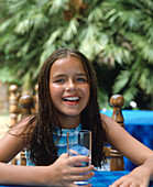 Smiling girl outdoor table holding glass of water
