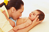 Woman kissing belly of a baby lying on his back