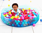 Boy playing in paddling pool filled with plastic balls