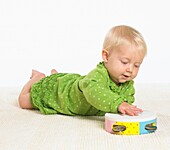 Baby girl lying on floor playing with a tambourine