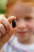Girl holding runner bean seed