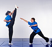 Girl performing axe kick, opponent stepping back