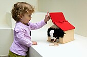 Baby girl playing with toy dog in kennel