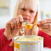 Woman scraping off excess formula from measuring spoon